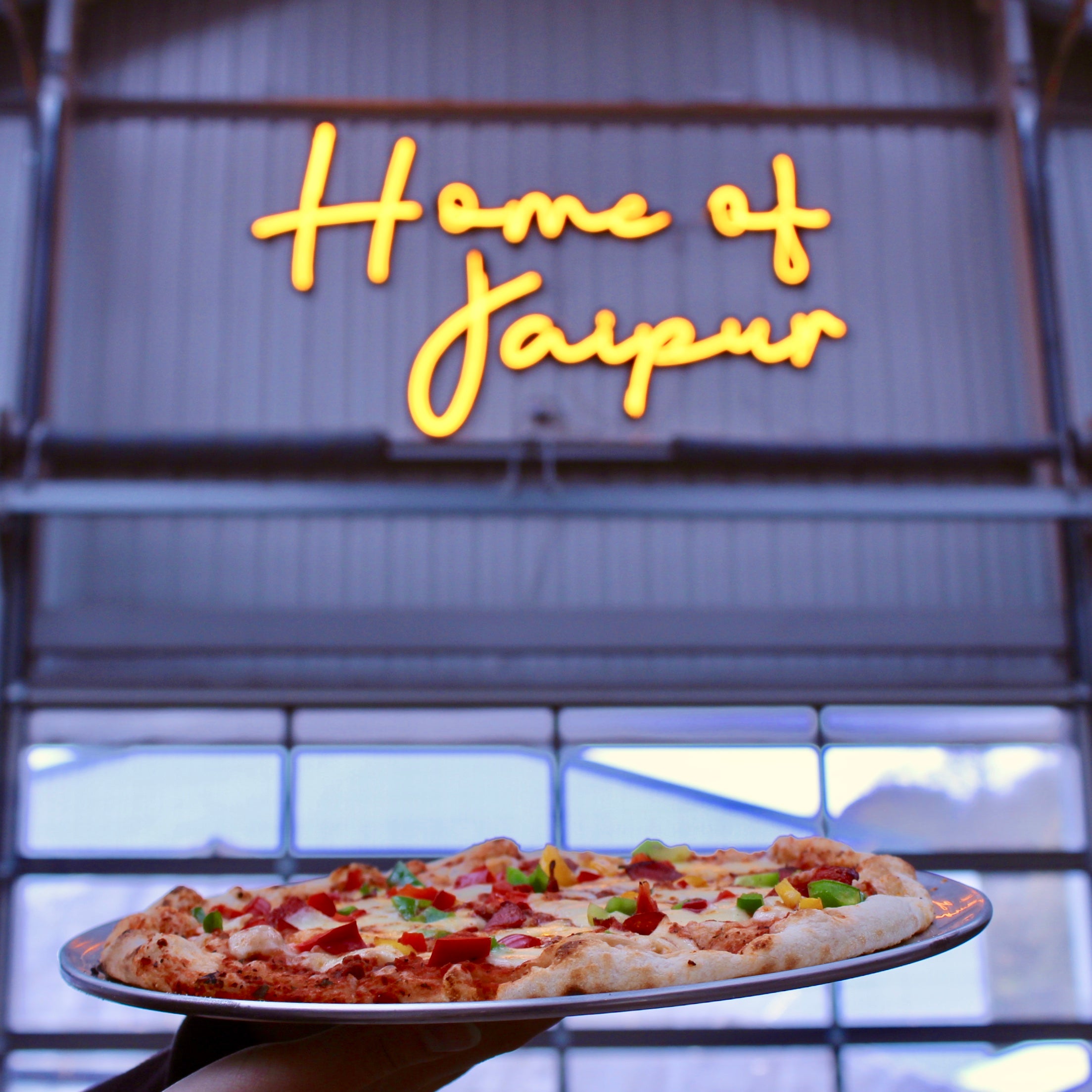 Inside the taproom with pizza and the home of jaipur neon sign