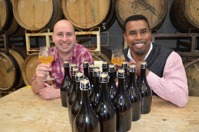 Image of Rob Lovatt and Garret Oliver behind freshly bottled Serpent beer