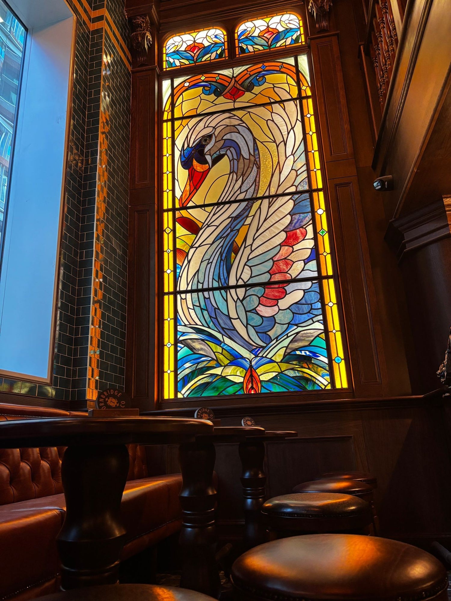 Stained glass window with a colorful swan design in The Wild Swan pubs
