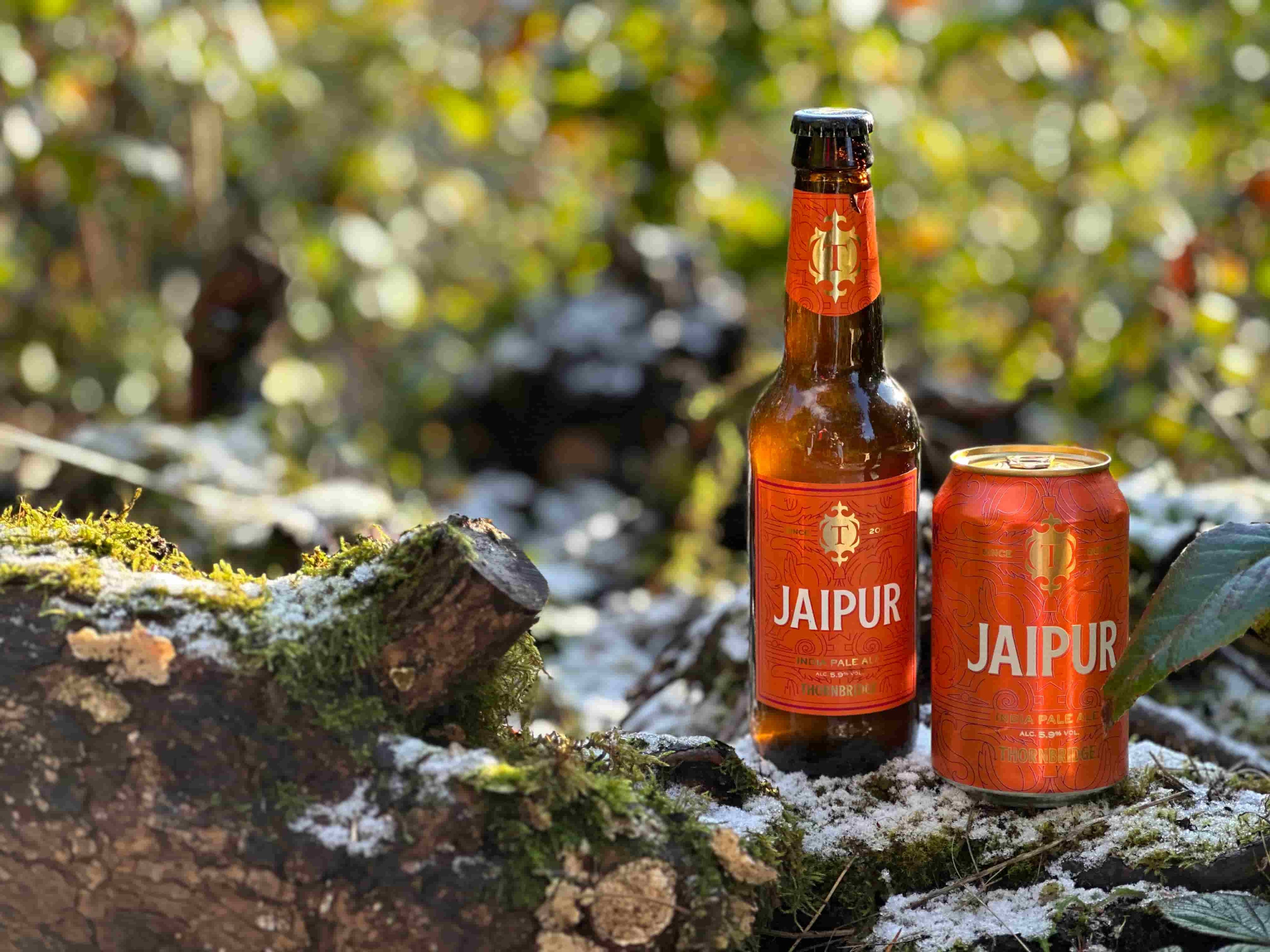 Jaipur can and Jaipur bottle on a snow covered log in the peak district