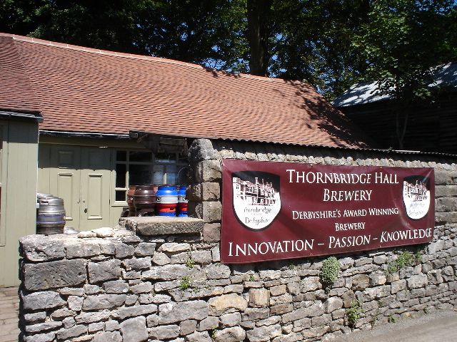 Thornbridge Hall Brewery sign on a stone wall with a rustic building in the background.